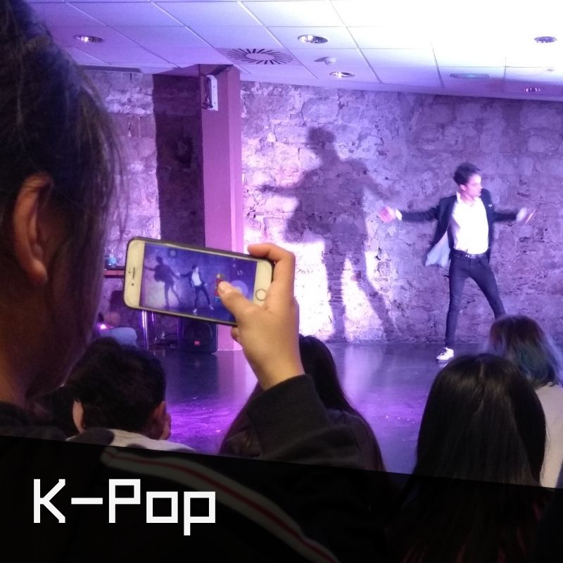 Exhibició de K-Pop, ballarí i noia jove amb mòbil fent les fotos de la performance