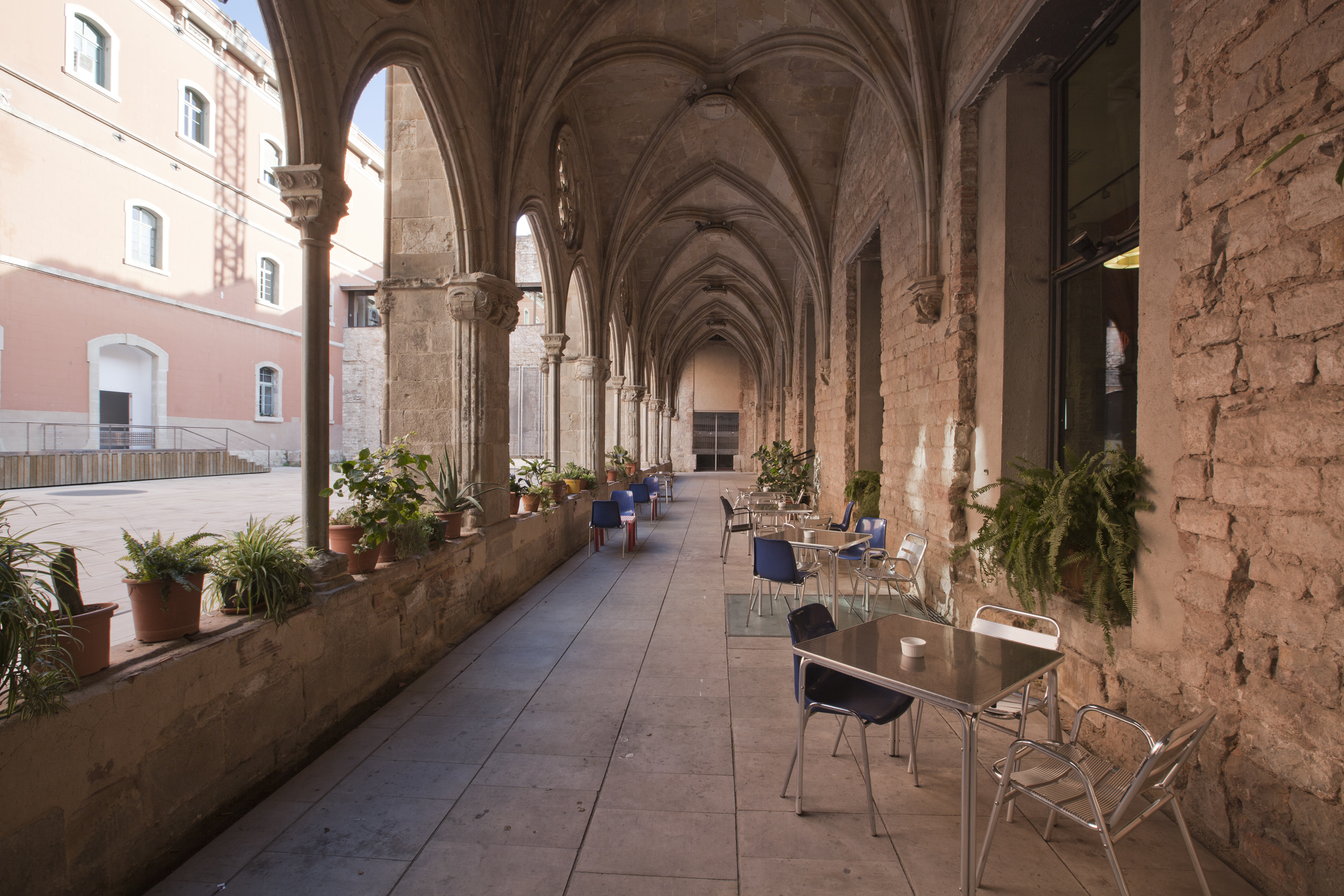 Imatge dels porxos laterals del claustre del Convent i les taules del bar del Convent. Fotografia realitzada per Mireia Plans.