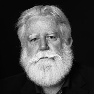 Foto de James Turrell en blanc i negre. Home amb el cabell blanc i una barba tofuda.